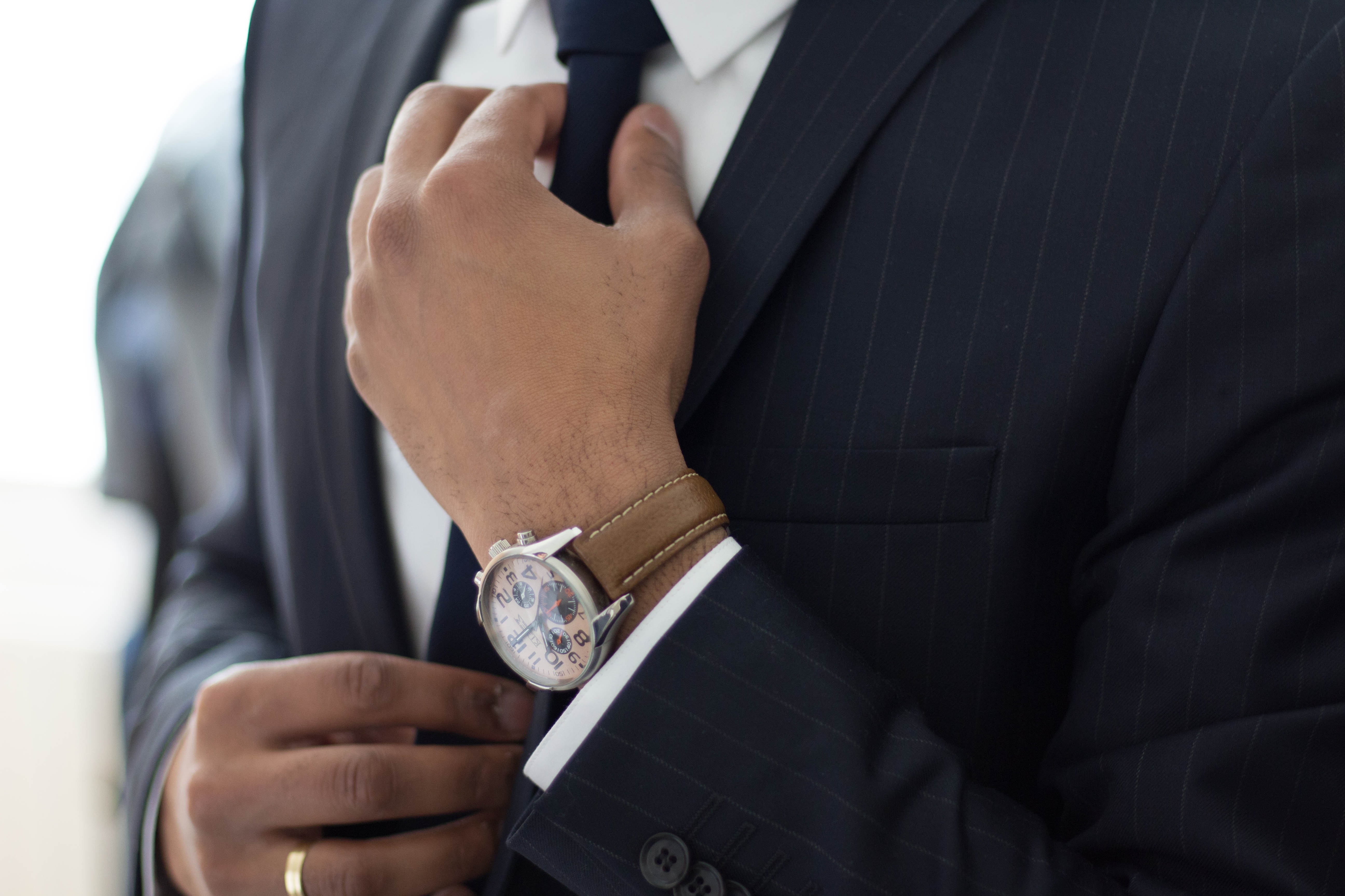 Close-up of a professional's hand adjusting a stylish wristwatch, symbolizing punctuality and preparation.