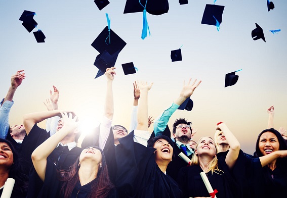 Group of graduates in caps and gowns celebrating, throwing their graduation caps in the air, symbolizing achievement and success.