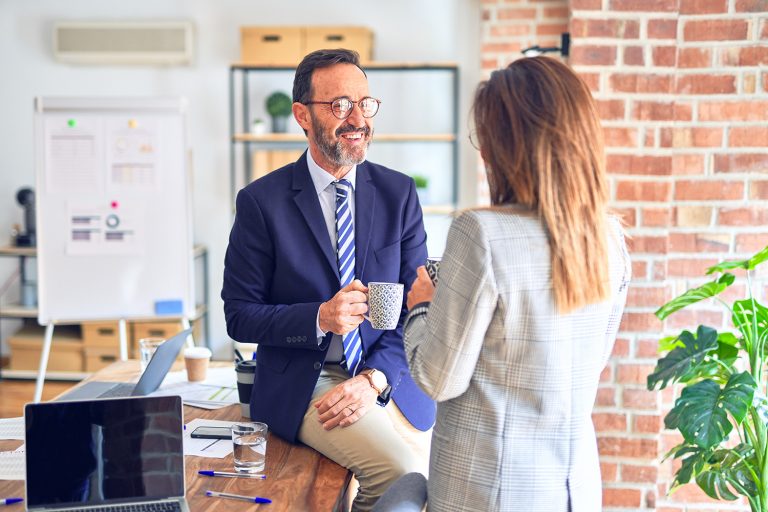 Businessman in a suit having a casual conversation with a female colleague in an office.