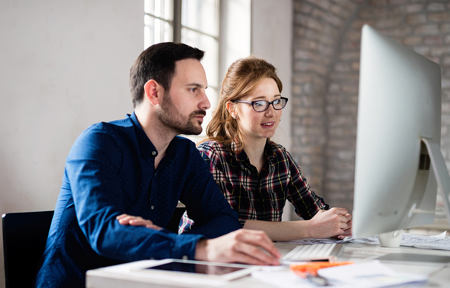 Two colleagues analyzing data on computer screen together.