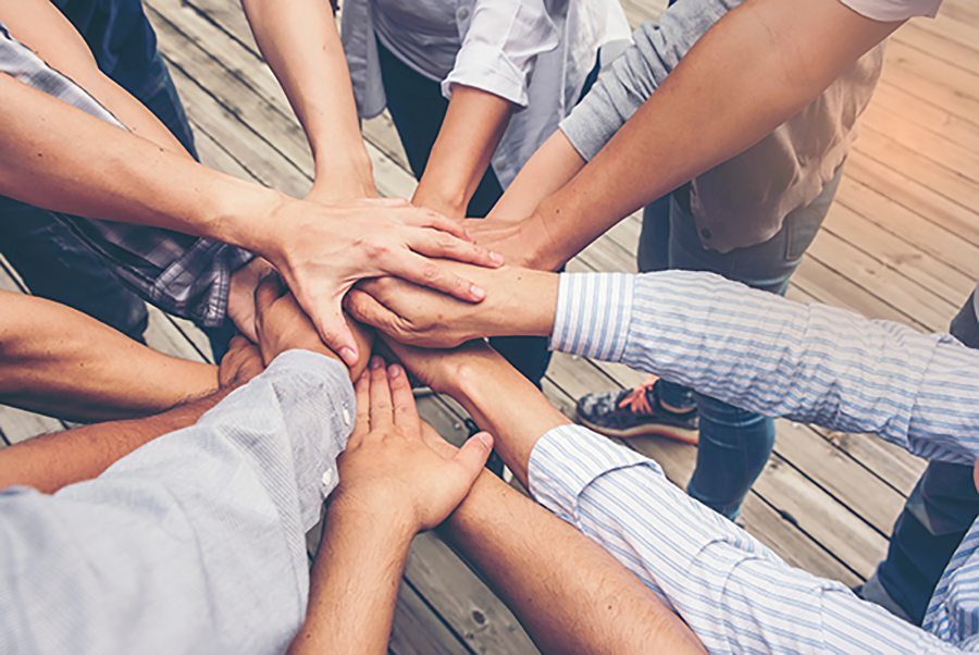 Team stacking hands together as a symbol of unity and teamwork.
