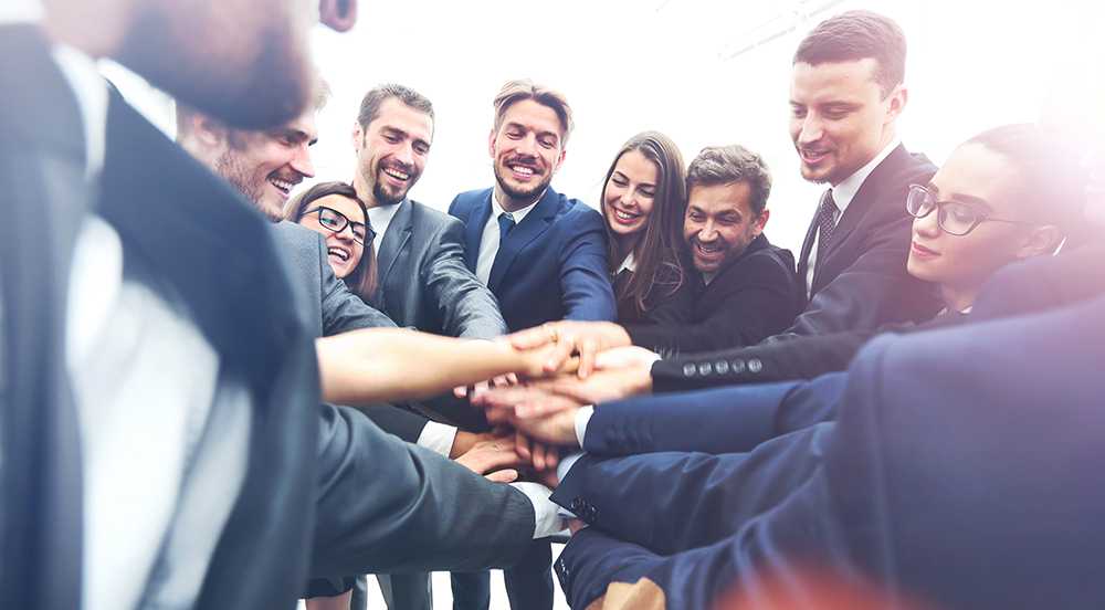 Team of professionals joining hands in unity for collaboration.
