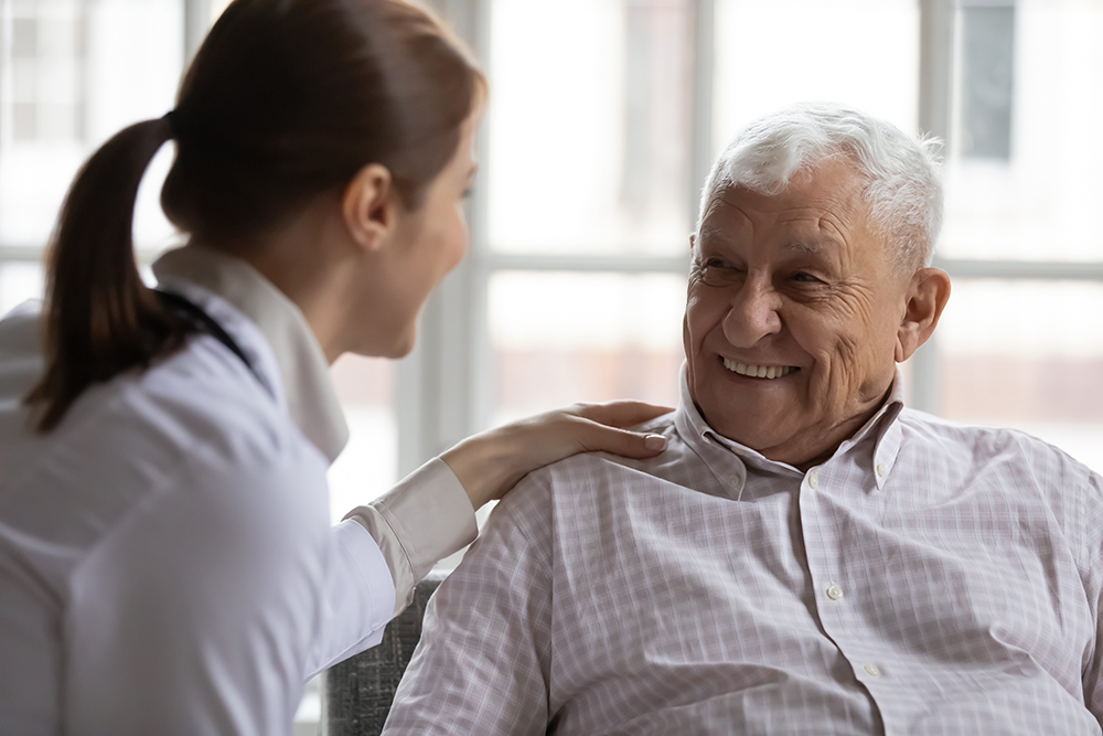 Senior man smiling during a conversation with a female colleague in an office setting.