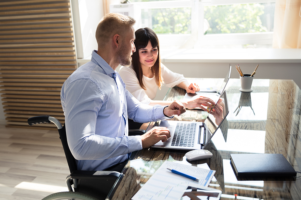 Two professionals collaborating on a computer in a bright office space.