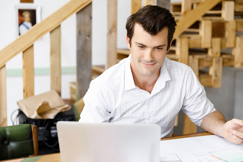 Focused man working on laptop in a home office.