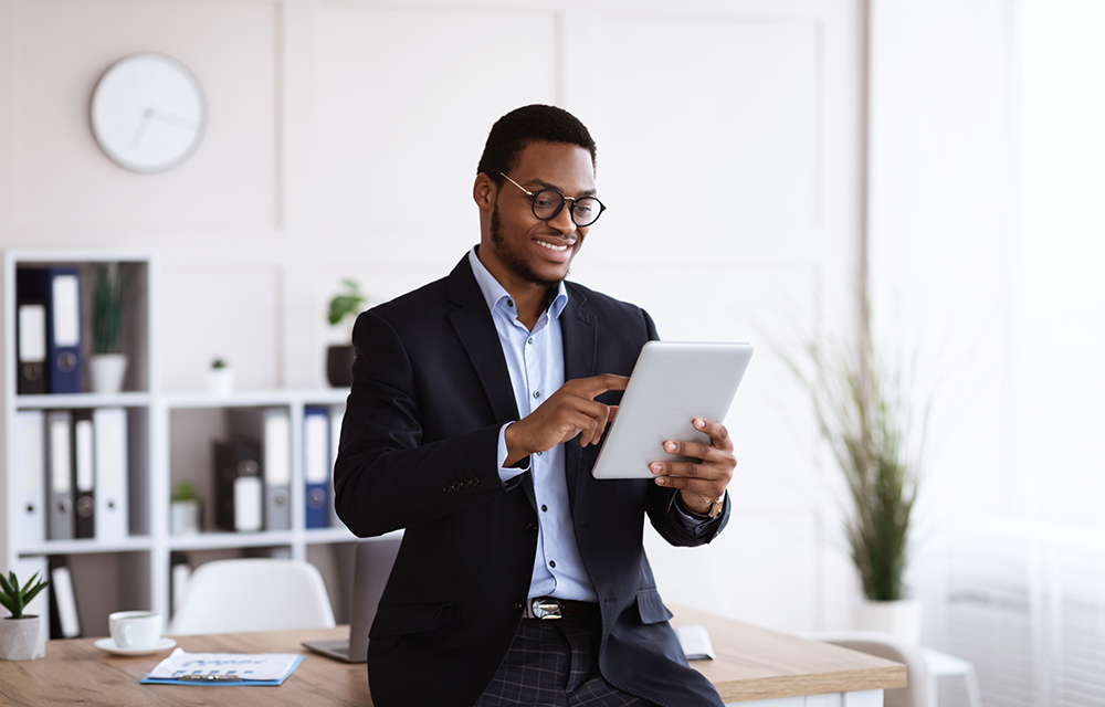 Smiling businessman using a tablet in a modern office.