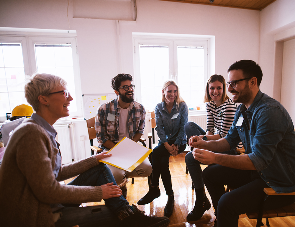 Diverse team laughing together during a casual office meeting.