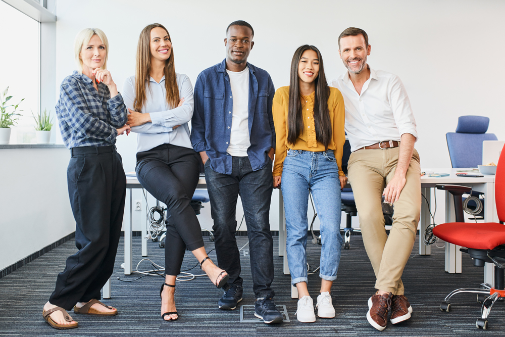 Smiling multiracial team standing confidently in a modern office setting.