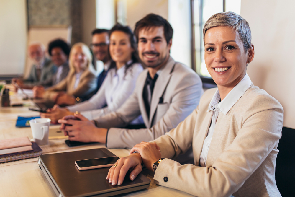 Confident businesswoman smiling at the camera with her diverse team in a meeting room.
