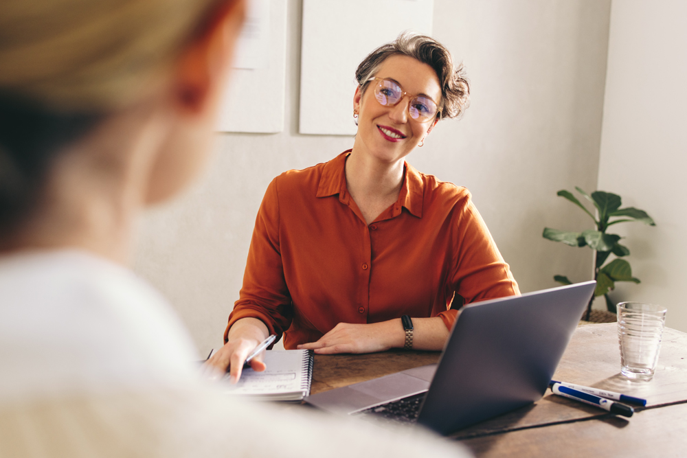 Confident businesswoman with glasses smiling during a consultation in an office setting.