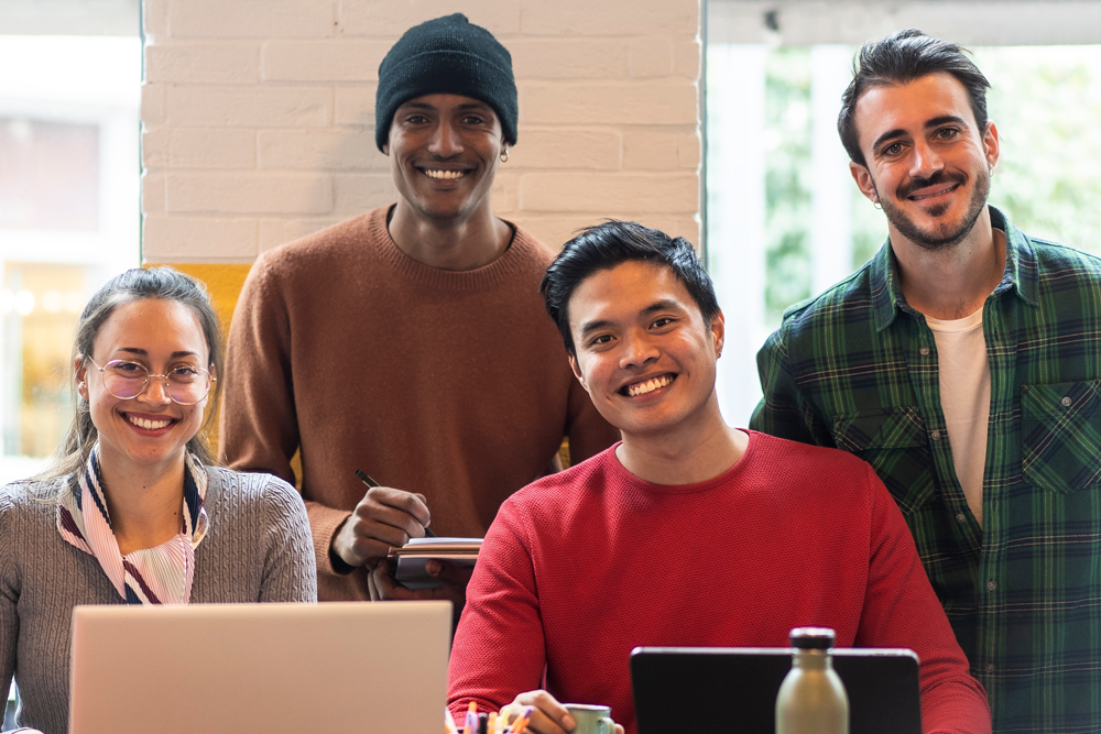 Diverse group of cheerful coworkers posing together in a creative workspace.
